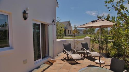a group of chairs and an umbrella on a patio at Wild Mushroom Country House in Stellenbosch