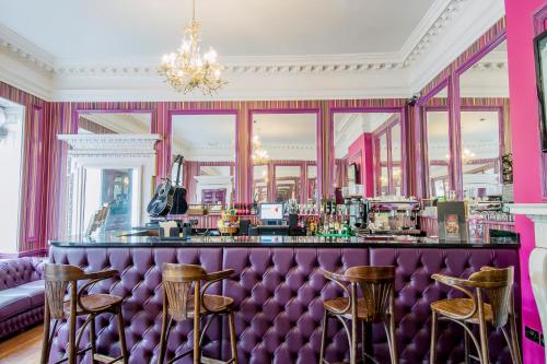 un bar en una habitación rosa con taburetes en Safestay York Micklegate, en York