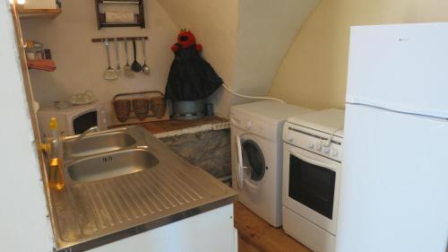 une cuisine avec un évier et une machine à laver dans l'établissement Le Seuil De Mes Reves, au Lauzet-Ubaye