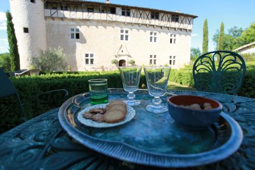 une table avec une assiette de nourriture et des verres à vin dans l'établissement Château de Mayragues, à Castelnau-de-Montmiral