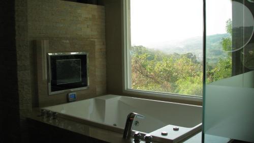a bathroom with a bath tub and a window at Milan Motel in Miaoli