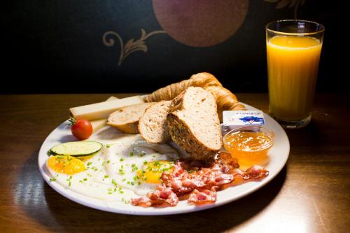 a plate of eggs and toast with bread and a glass of orange juice at Gasthaus zum Guten Glück in Zurich