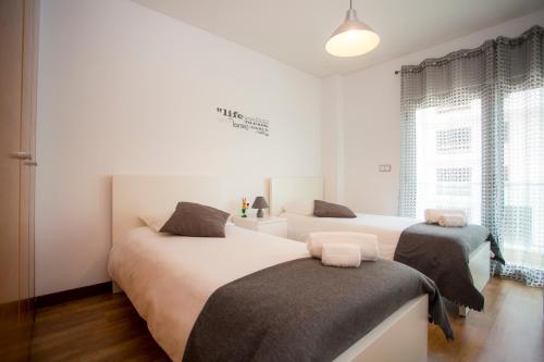 Un dormitorio con dos camas y una ventana. en Surf and Stones Apartment, en Peniche