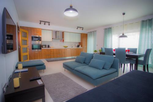 a living room with a blue couch and a kitchen at Surf and Stones Apartment in Peniche