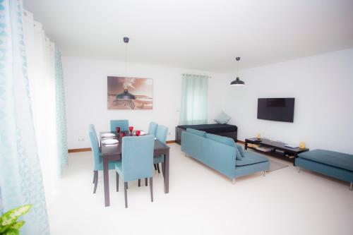 a living room with a table and blue chairs at Surf and Stones Apartment in Peniche