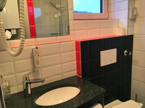 a bathroom with a sink and a mirror at UNO Hotel Chapeau Noir - Free Parking in Überherrn