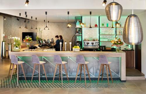 a bar in a restaurant with purple stools at Park Inn By Radisson Hasselt in Hasselt