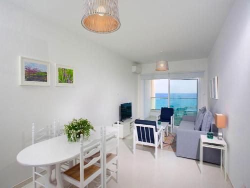 a white living room with a table and a couch at On The Beach Penthouse by TrulyCyprus in Limassol