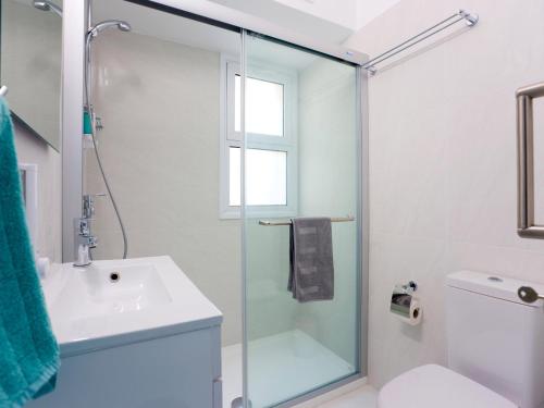 a bathroom with a sink and a glass shower door at On The Beach Penthouse by TrulyCyprus in Limassol