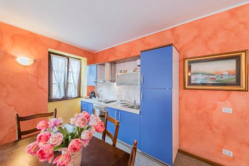 a kitchen with a blue refrigerator and a table with flowers at Villa Edy Apartments in Tremezzo