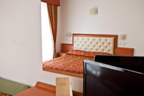 a bedroom with a bed and a desk with a tv at Hotel Gabbiano in Riccione
