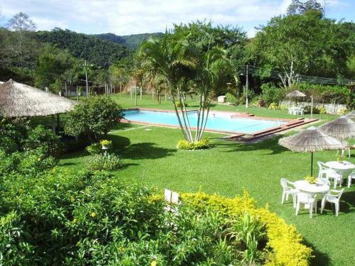 einen Garten mit einem Pool mit Tischen und Sonnenschirmen in der Unterkunft Parque Hotel Morro Azul - a 12 km do Parque dos Dinossauros in Morro Azul