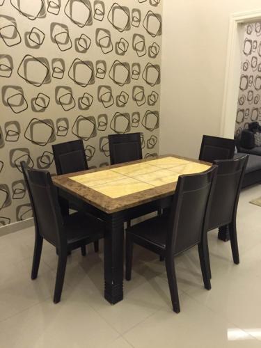 una mesa de madera con sillas negras y una pared en Rukon Buotat 15, en Riad