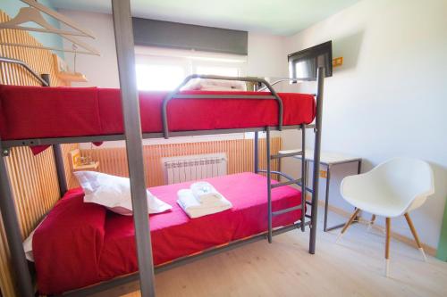 a bedroom with two bunk beds and a chair at Pension Restaurante Casa Camiño in Palas de Rei 