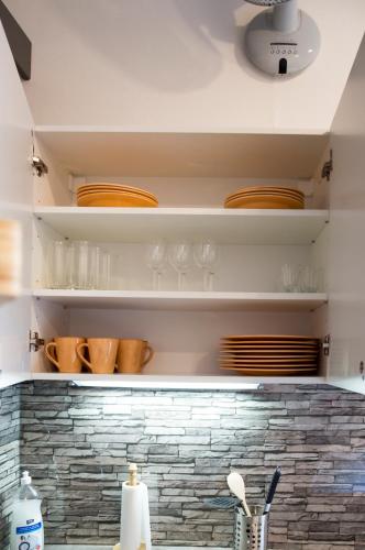 a kitchen with plates and bowls on shelves at Design Apartment Havelska in Prague