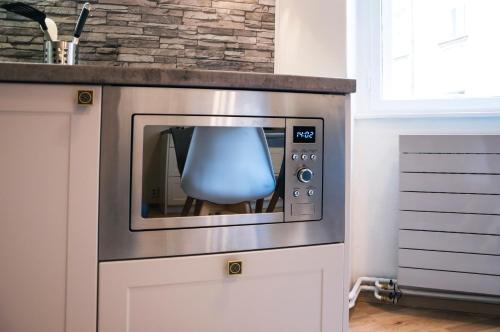 a microwave oven with a blue chair sitting on top of it at Design Apartment Havelska in Prague