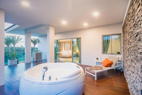 a large white tub in a room with a couch at The Peak in Chanthaburi