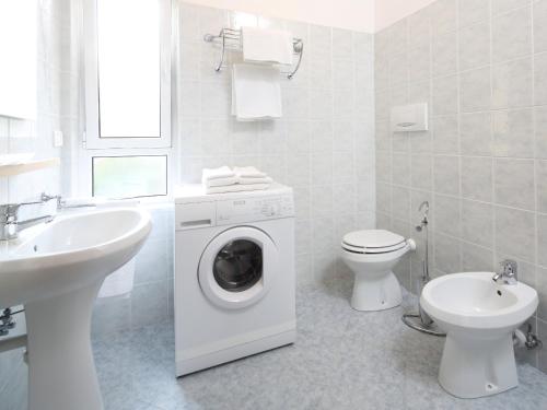 La salle de bains blanche est pourvue d'un lave-linge et d'un lavabo. dans l'établissement Villa Delle Ciliegie, à Deiva Marina