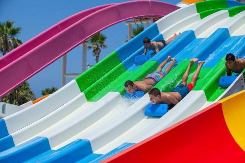 a group of children playing on a water slide at a water park at Leonardo Laura Beach & Splash Resort in Paphos City