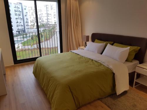 een slaapkamer met een groot bed en een groot raam bij Appartement avec Piscine à Hay Riad in Rabat