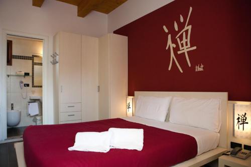 a bedroom with a red and white bed with two towels at Hotel Santa Lucia in Bibione
