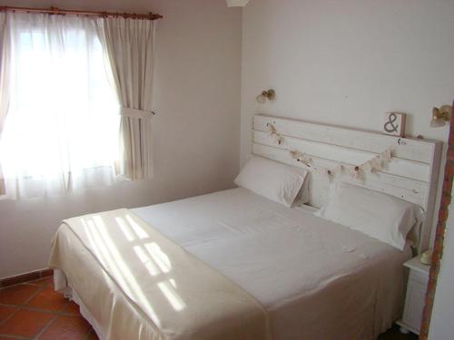 a white bed in a bedroom with a window at Los Tulipanes Apart de Mar in Puerto Madryn