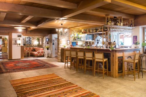 a large room with a bar with chairs and a couch at Berghotel - Sexten in Sesto