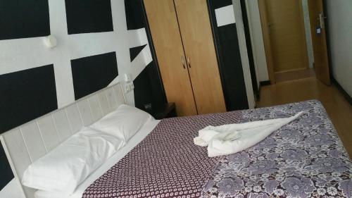 a bed with a white towel on top of it at Hostal Lima in Valladolid