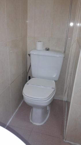 a bathroom with a white toilet in a tiled room at Hostal Lima in Valladolid