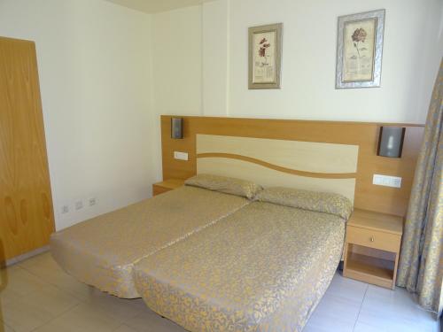 ein Schlafzimmer mit einem Bett mit einem Kopfteil aus Holz in der Unterkunft Apartamentos Selvapark in Lloret de Mar