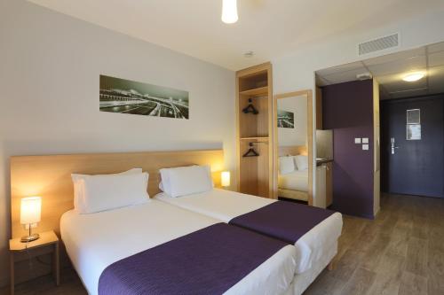 - une chambre avec un grand lit dans une chambre d'hôtel dans l'établissement EastLodge Lyon Est Eurexpo, à Saint-Priest