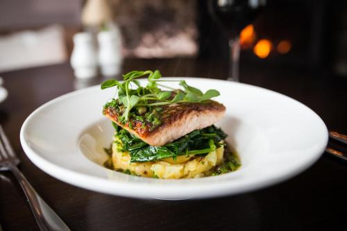 a white plate with a fish dish on a table at Black Horse Hotel in Grassington