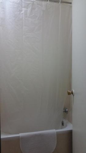 a bathroom with a tub and a white shower curtain at Hostal Lima in Valladolid