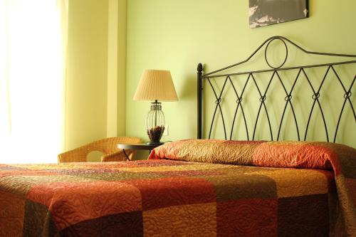 a bedroom with a bed and a table with a lamp at Hostal Zaguan in Talaveruela