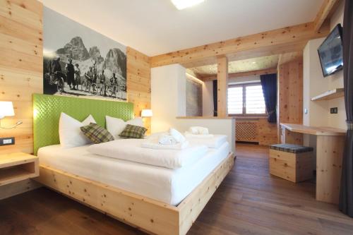 una camera con un grande letto in una stanza con pareti in legno di DOLOMITES B&B - Suites, Apartments and SPA a Tesero