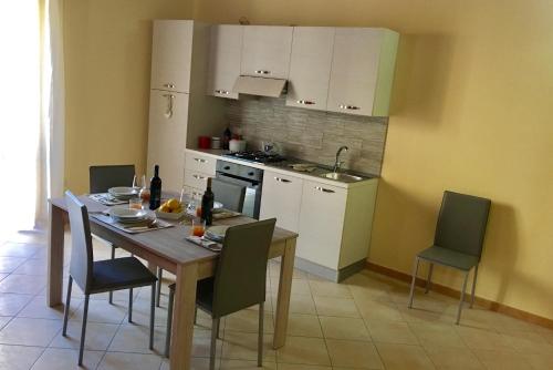 a kitchen with a wooden table and chairs and a kitchen with white cabinets at Al Duomo in Partinico