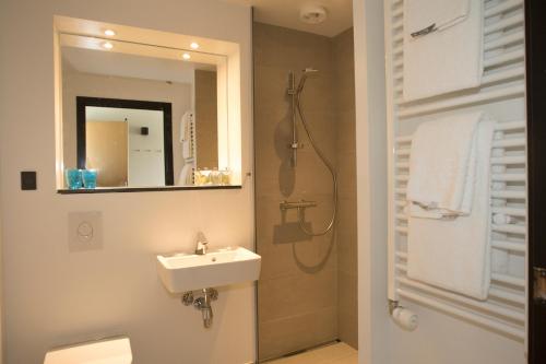 a bathroom with a sink and a shower with a mirror at Hotel 6400 in Sønderborg