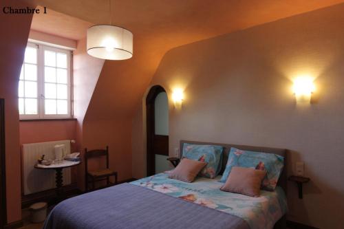 1 dormitorio con 1 cama con sábanas azules y almohadas rosas en La Demeure du Castel en Rospez