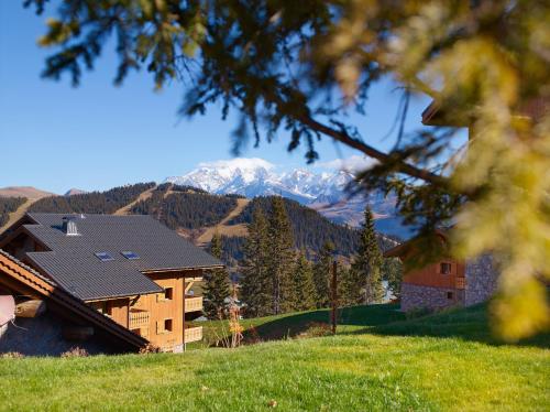 une maison sur une colline avec une montagne en arrière-plan dans l'établissement CGH Résidences & Spas Le Hameau Du Beaufortain, aux Saisies