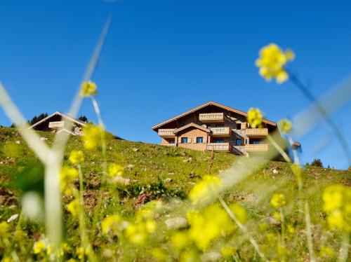 une maison au sommet d'une colline avec des fleurs jaunes dans l'établissement CGH Résidences & Spas Le Hameau Du Beaufortain, aux Saisies
