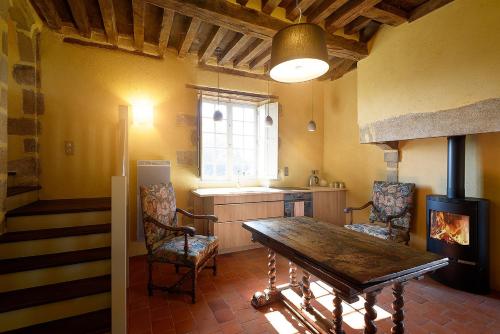 uma cozinha com uma mesa e cadeiras e uma lareira em La Porterie em Souvigny