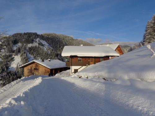 a building covered in snow next to a snow covered road at Apartment Lehengut in Eben im Pongau