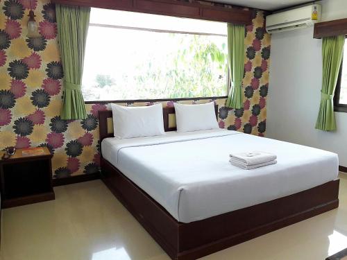 ナコーン・ラーチャシーマーにあるโรงแรมฟ้าพราวฝน Fah Proud Fon Hotelの白いシーツと窓のあるベッドのある寝室