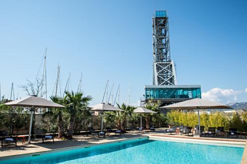 a pool with umbrellas and a tower in the background at Hôtel Mercure Toulon La Seyne-Sur-Mer in La Seyne-sur-Mer