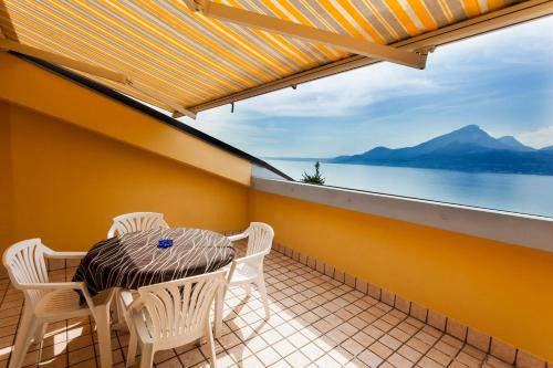 a balcony with a table and chairs and a view of the water at Taki Village in Brenzone sul Garda