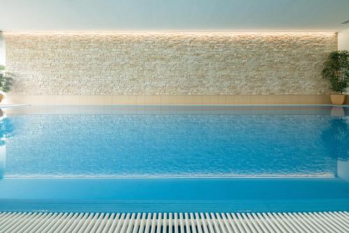 a swimming pool with blue water in a building at Hotel Bellevue in Timmendorfer Strand