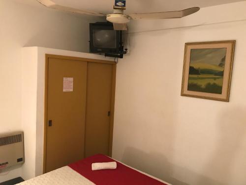 Habitación con cama y TV en la pared. en Hotel Antares, en Montevideo