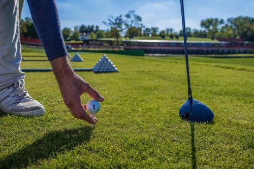 a man holding a golf ball next to a golf club at Villaverde Hotel Spa&Golf Udine in Fagagna