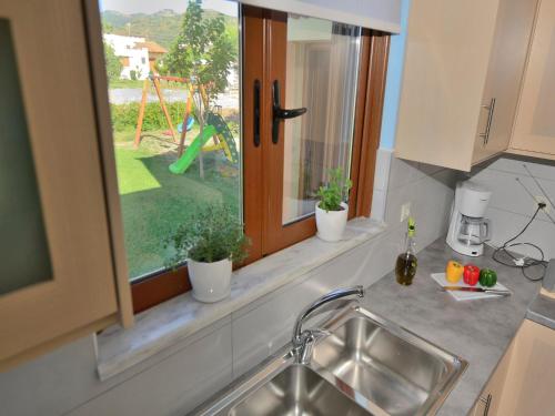 een keuken met een wastafel en een raam met een speeltuin bij Niriides Apartments in Kissamos