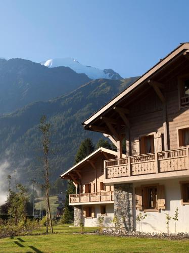un bâtiment avec un balcon et des montagnes en arrière-plan dans l'établissement CGH Résidence Boutique Le Hameau De Pierre Blanche, aux Houches